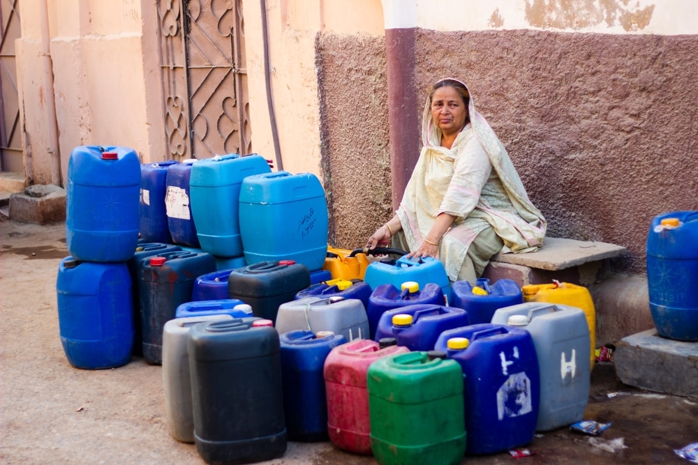Pakistani Woman Sitting Near Water Pump With Gallons